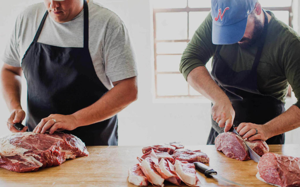 Two men slicing meat