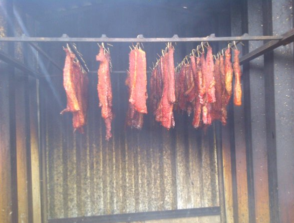 Smoked brisket hanging over a fire pit in Guam